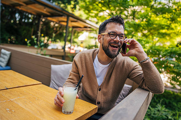istock Happy man talking on phone and drinking lemonade in outdoor cafe 2217760087