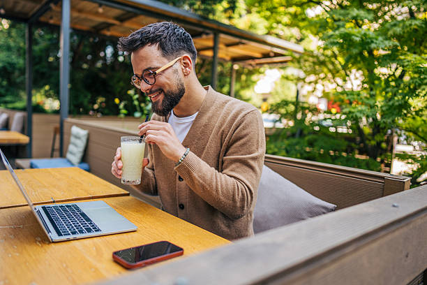 istock Freelancer enjoying a refreshing drink while working on laptop at outdoor cafe 2217760134