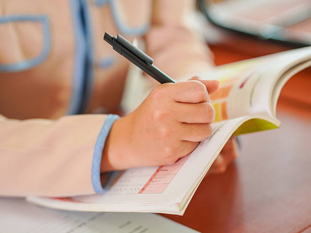 istock Closeup of teacher or student's hand writing, taking notes in classroom at kid school 2217760819