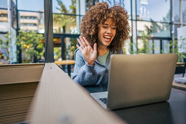 istock Young woman waving during a video call at a cafe 2217760888
