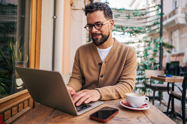 istock Freelancer working on laptop at outdoor cafe, enjoying cappuccino 2217761347