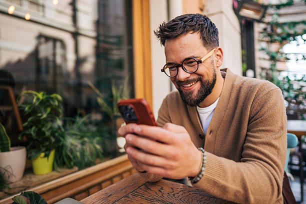 istock Smiling male freelancer using smartphone at outdoor cafe 2217761436