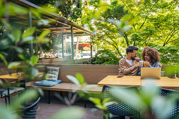 istock Young couple using laptop and drinking juice at outdoor cafe 2217761580