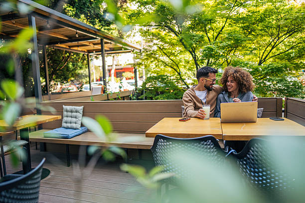 istock Young couple using laptop and smiling at outdoor cafe 2217761609