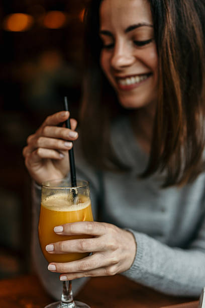 Young woman enjoying fresh orange juice in a cafe