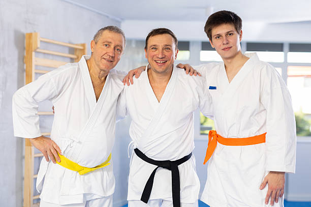 istock Three generations of martial arts fighters friendly embracing in training room 2217764398