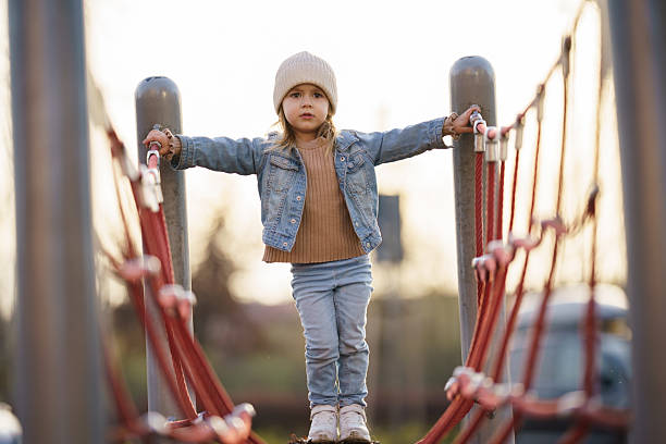 Cute little girl having fun climbing on a net at the playground
