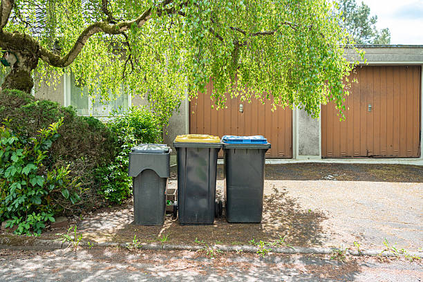 istock Recycling Bins Under Tree Outside Garage Doors 2217767020