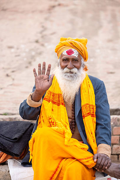 Varanasi, Uttar Pradesh, India - January 2024: Portrait of an old holy sadhu baba in traditional dress sitting on the ghats near ganges in varanasi.
