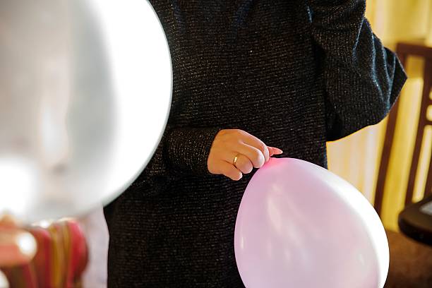 istock Hands tying a pink balloon during party preparation indoors 2217774111