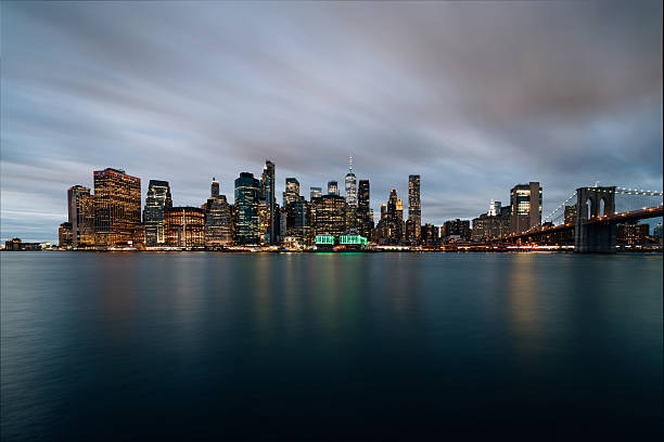 Manhattan skyline at night seen from Brooklyn. Famous landmark of Lower Manhattan and Brooklyn Bridge.