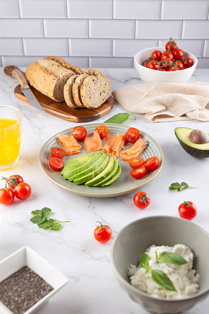 istock Healthy breakfast with avocado, salmon, whole grain bread and cherry tomatoes on a light tiled background. Balanced nutrition. Concept of natural breakfast and healthy lifestyle 2217780389