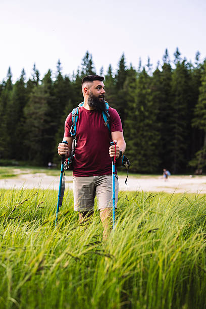 istock Hiker walking through tall grass near forest and lake 2217782455