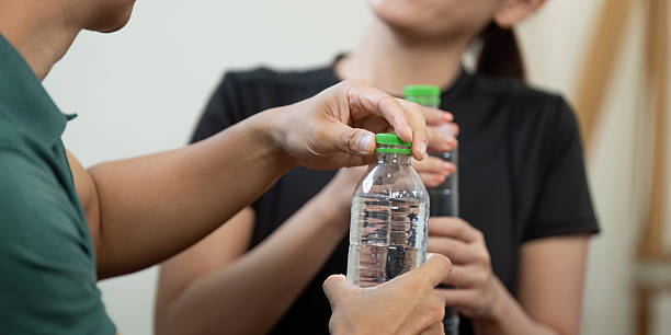 istock Couple Sharing Water Bottles. Two fitness enthusiasts exchanging hydration during workout session. 2217786324