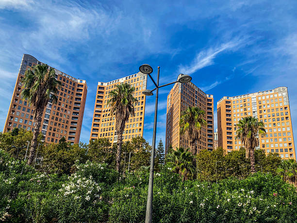 Upward view of a tall streetlight pole silhouetted against massive cumulus clouds, with sunlight breaking through the clouds and creating radiant beams, symbolizing contrast between urban elements and natural beauty.
