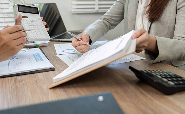 istock Financial Strategy Discussion. Professionals reviewing financial documents and using a calculator. 2217789777