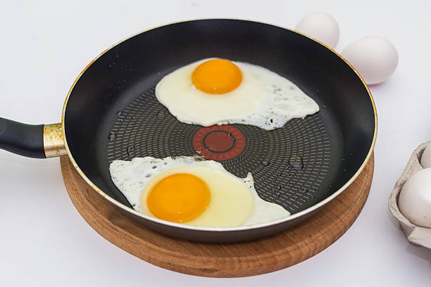 In the process of preparing breakfast with fresh eggs. Fried eggs from two eggs in a frying pan.