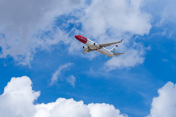 Spain, Majorca, Palma de Mallorca, May 05, 2025 - Low angle view of Norwegian airline plane taking off against cloudy sky