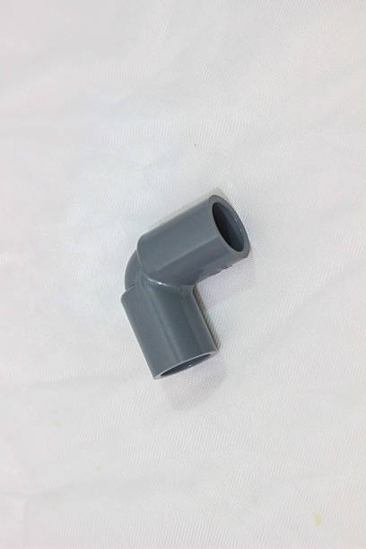 istock A gray plastic elbow pipe fitting lies on a white textured surface, showing a smooth, curved 90-degree angle designed to connect two pipes. 2217795744