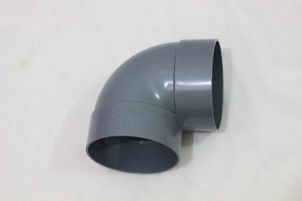 istock Close-up of a gray plastic pipe elbow fitting positioned upright on a white textured surface, showing its smooth curved shape and hollow interior. 2217796451