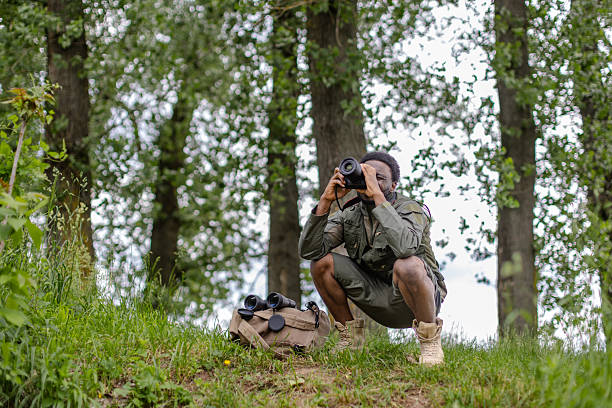 istock Bird watcher enjoying nature in a forest while capturing photographs with binoculars and a camera 2217805244