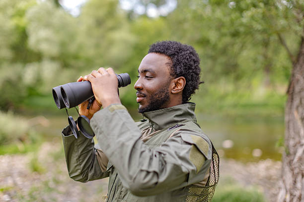 istock Bird watcher enjoying nature with binoculars by the serene forest river 2217805451