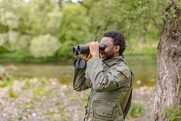 istock Bird watching adventure in a serene forest setting with a cheerful young man using binoculars 2217805557