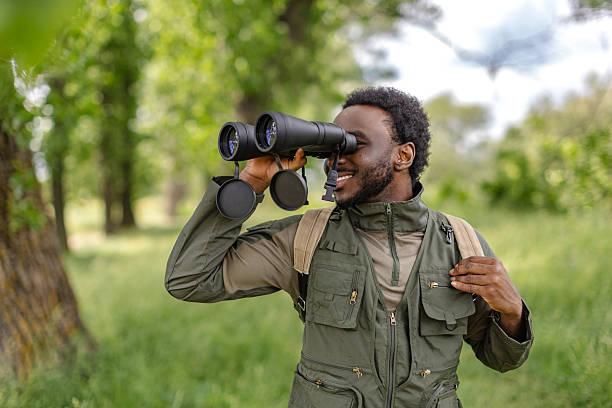 istock Bird watching adventure with young man using binoculars in a lush forest setting 2217805618