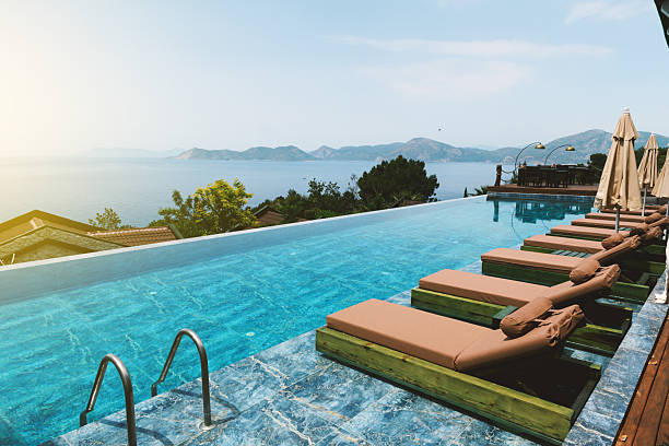 Mature woman relaxes in swimming pool, sea and village below