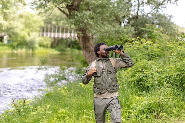 istock Curious birdwatcher exploring nature with binoculars by the river in a serene forest setting 2217806290
