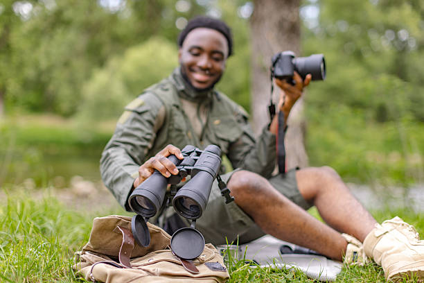 istock Curious young man exploring nature with binoculars and camera in a lush forest setting 2217806677