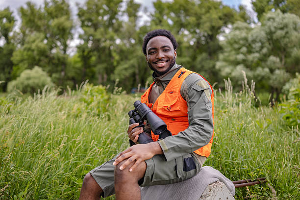 istock Joyful young man bird watching in the forest while holding binoculars and enjoying nature's beauty 2217807778