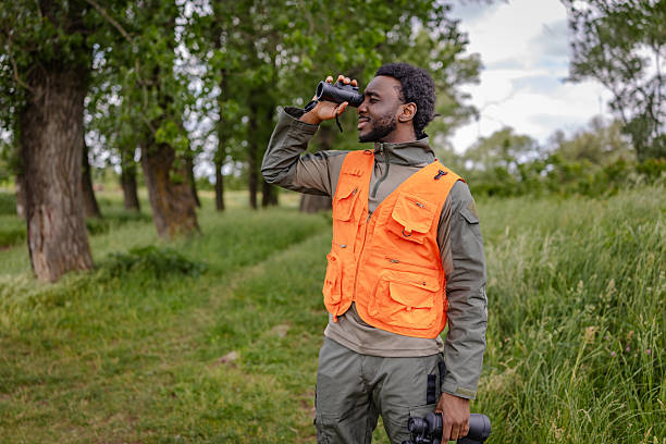 istock Young man bird watching in a lush green forest while enjoying nature and exploration on a cheerful weekend adventure 2217808670