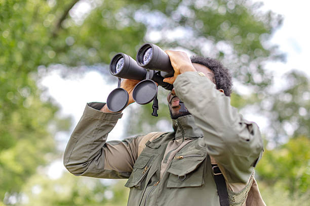istock Young man bird watching in the forest with binoculars on a cheerful weekend adventure 2217808892