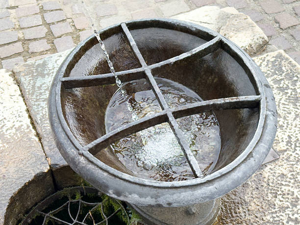 Historic stone fountain with grid design on cobblestone street, lifestyle