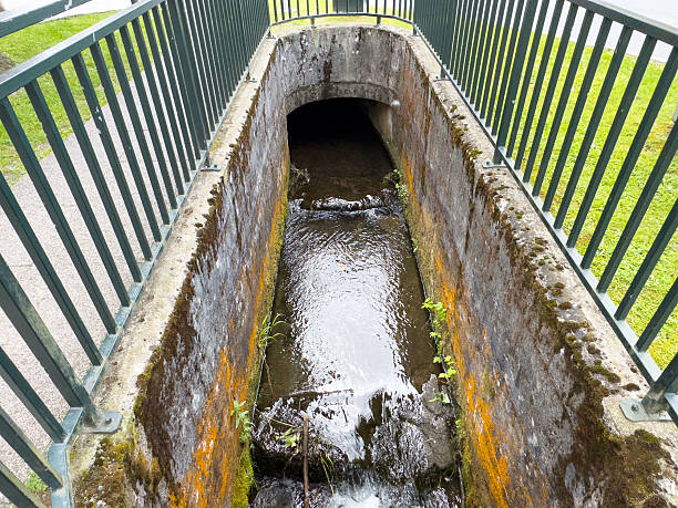 istock Mossy concrete canal under bridge with flowing water in urban park setting 2217809648