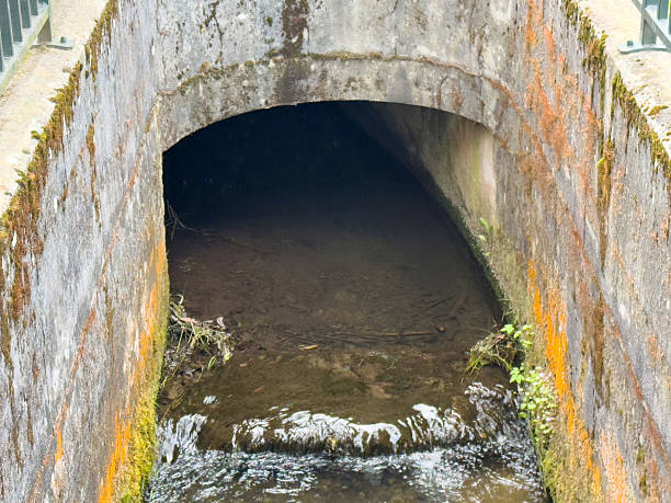 istock Water flowing through old concrete drainage tunnel with mossy walls 2217809687