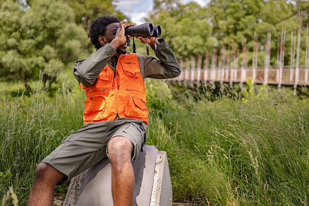 istock Young man enjoying bird watching in a lush forest setting with binoculars 2217810044