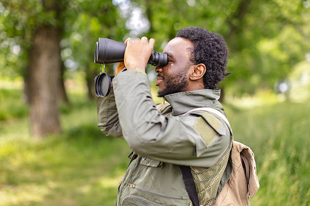 istock Young man enjoying bird watching in a lush forest, exploring nature with binoculars during a sunny weekend 2217810235