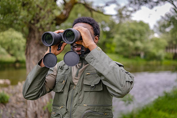istock Young man enjoying bird watching with binoculars in a serene outdoor forest setting 2217810670