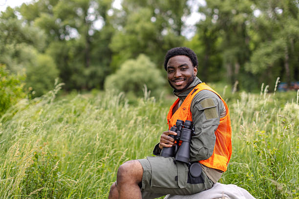 istock Young man enjoying birding adventure in a lush forest while holding binoculars on a sunny weekend 2217810728
