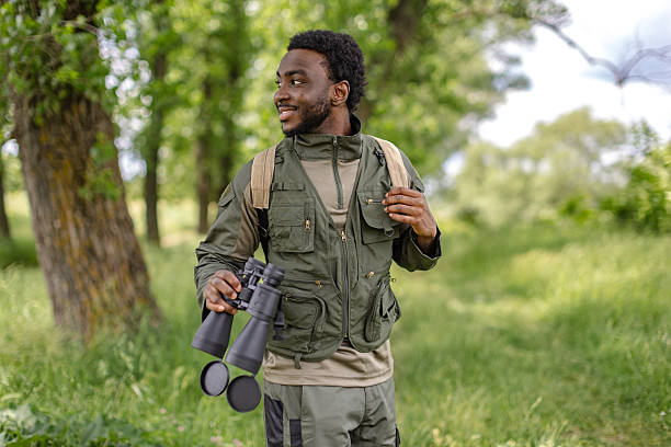 istock Young man enjoying birdwatching in a lush forest setting with binoculars on a cheerful outdoor adventure 2217810771