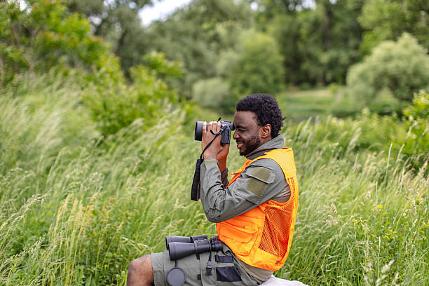 istock Young man enjoys bird watching in a lush forest while capturing wildlife moments with a camera 2217811259