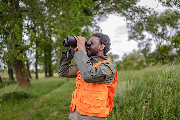 istock Young man enjoys bird watching in a lush green forest while exploring nature with binoculars 2217811828
