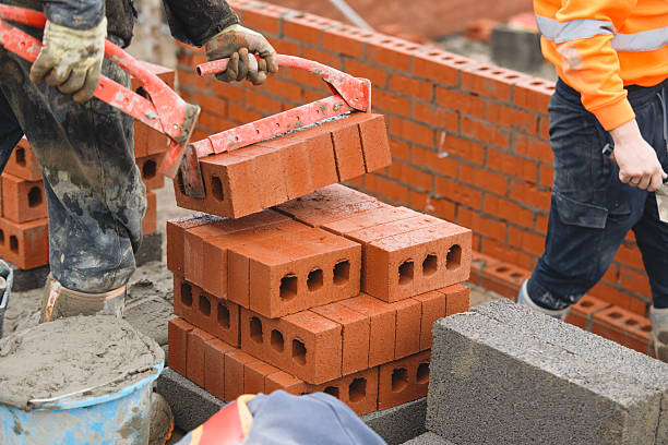 istock Bricklayer moving and stacking red bricks at busy building using brick tongs lifting carrier, showcasing dedication to craftsmanship and urban development 2217812009