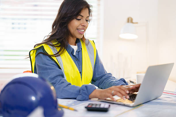 istock Female land surveyor reviews plans while using smartphone and laptop during office hours at project site 2217812144