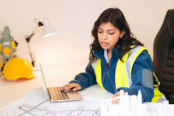 istock Female Professional builder engineer working with building plans while seated at desk in office 2217812254