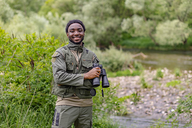 istock Young man enjoys bird watching with binoculars by the river in a lush forest during a weekend adventure 2217812373