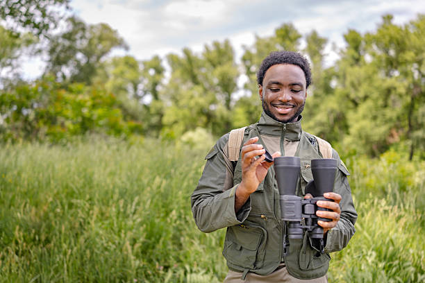 istock Young man enjoys birding with binoculars in a lush forest on a cheerful weekend adventure 2217812580