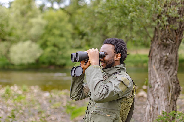 istock Young man watches birds with binoculars in a serene forest setting during a weekend adventure in nature 2217812909